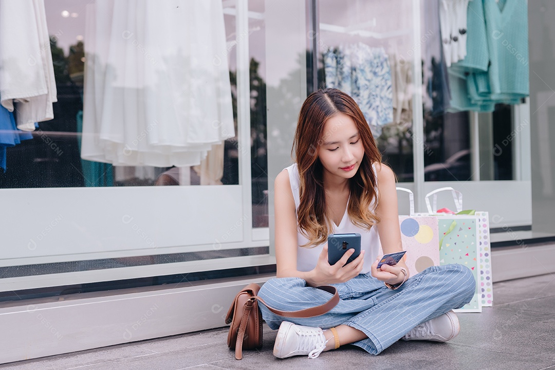 Mulher asiática cliente compradora usando cartão de crédito e smartphone para pagamento