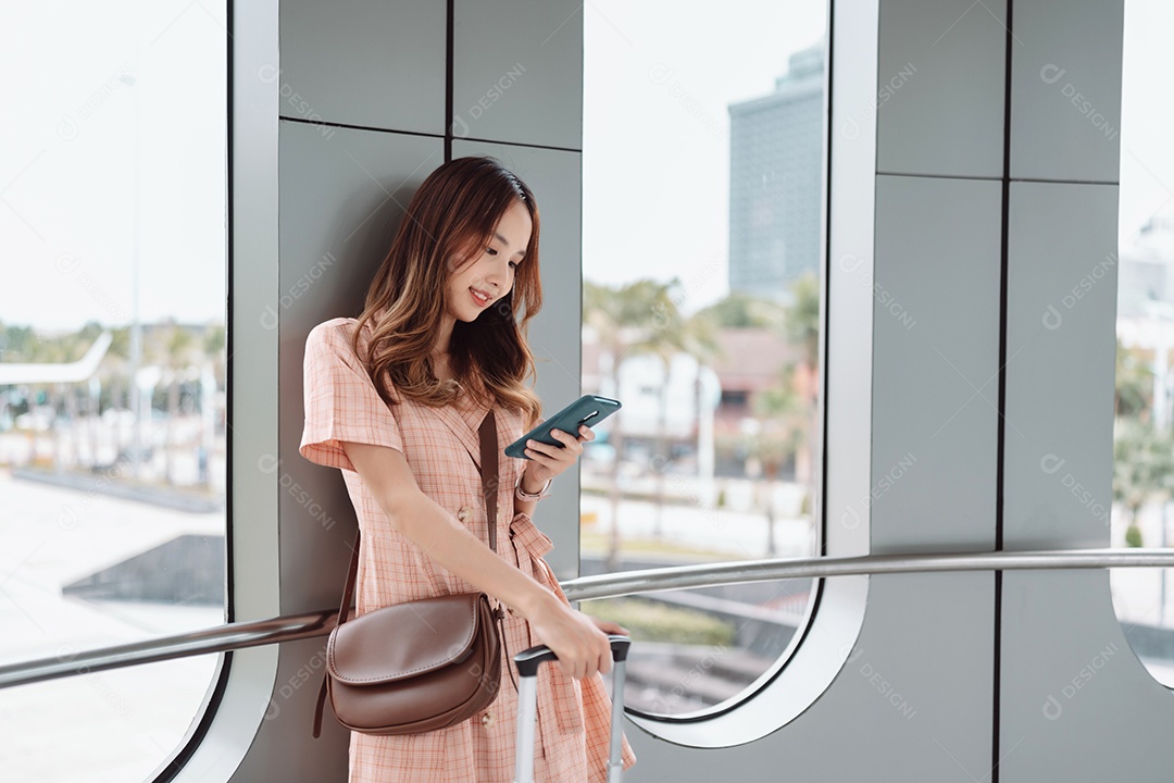 Mulher asiática adolescente usando smartphone no terminal do aeroporto