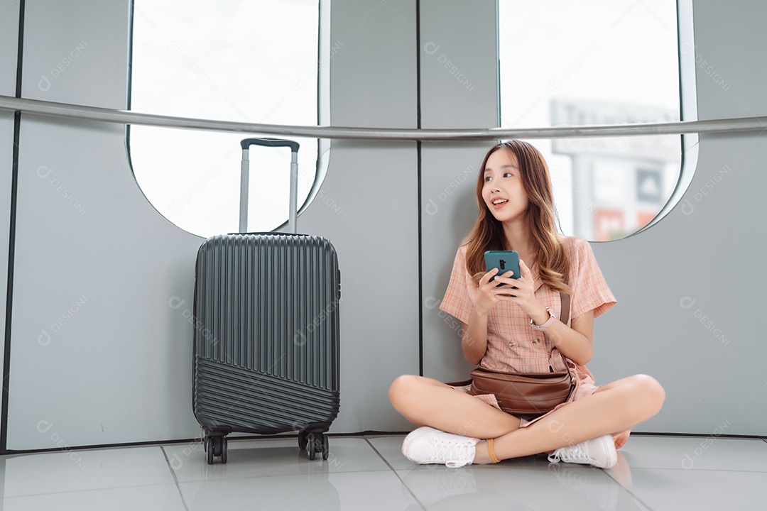 Mulher asiática adolescente usando smartphone no terminal do aeroporto