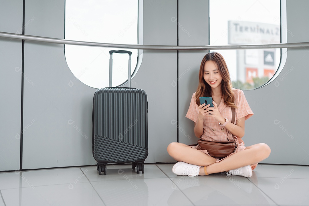 Mulher asiática adolescente usando smartphone no terminal do aeroporto