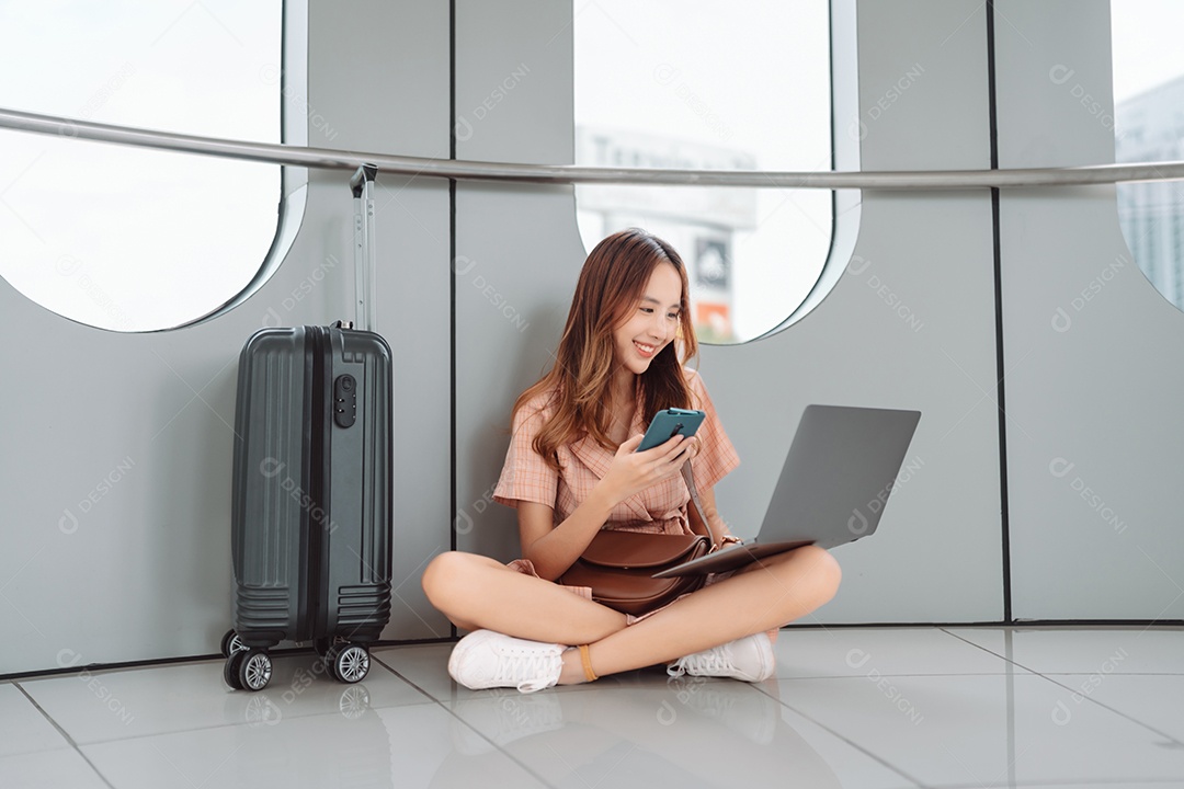 Mulher asiática jovem usando laptop no terminal do aeroporto