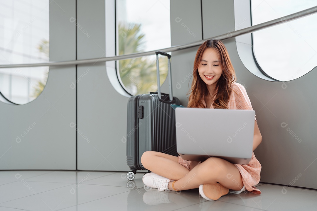 Mulher asiática jovem usando laptop no terminal do aeroporto
