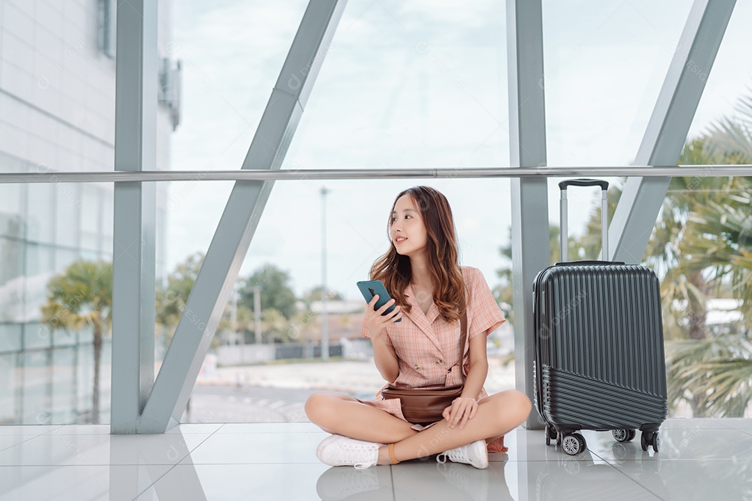 Mulher asiática adolescente usando smartphone no terminal do aeroporto