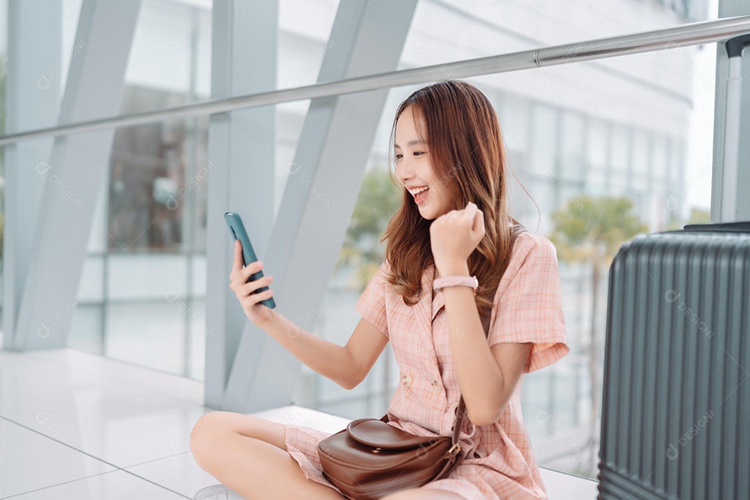 Mulher asiática adolescente usando smartphone no terminal do aeroporto