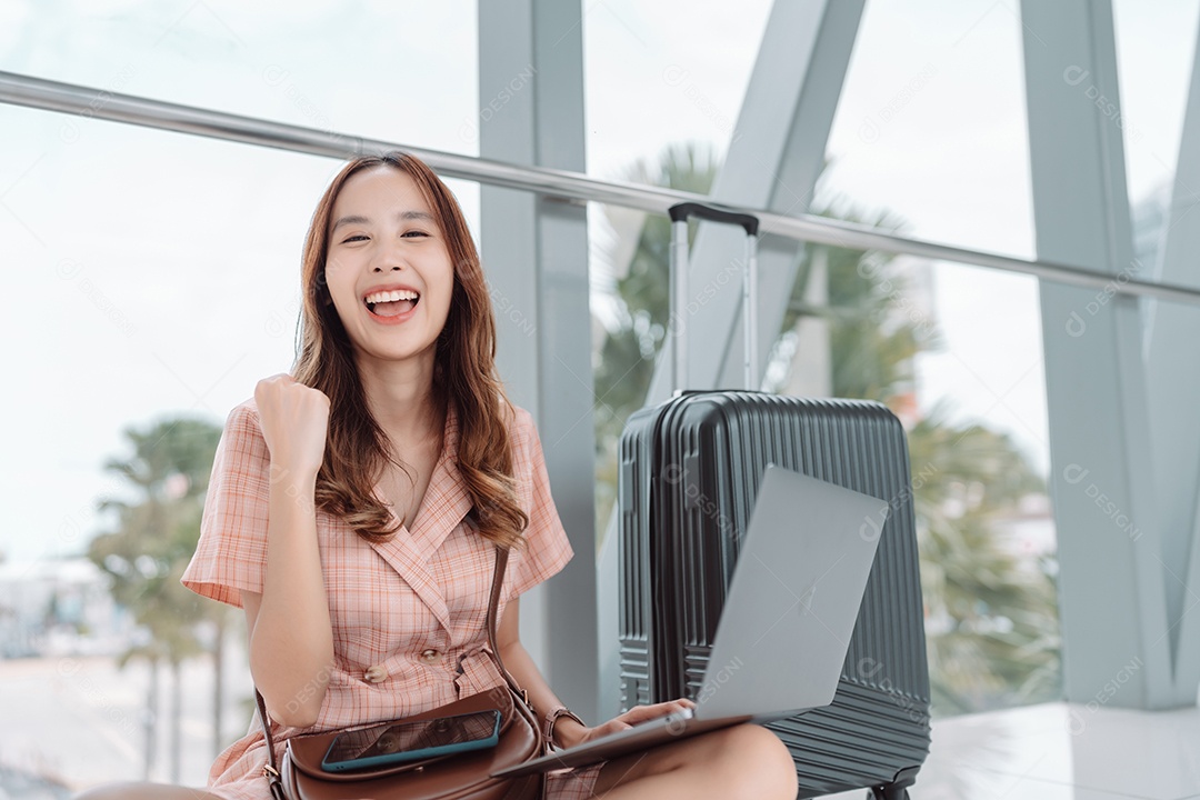 Mulher asiática adolescente usando laptop no terminal do aeroporto