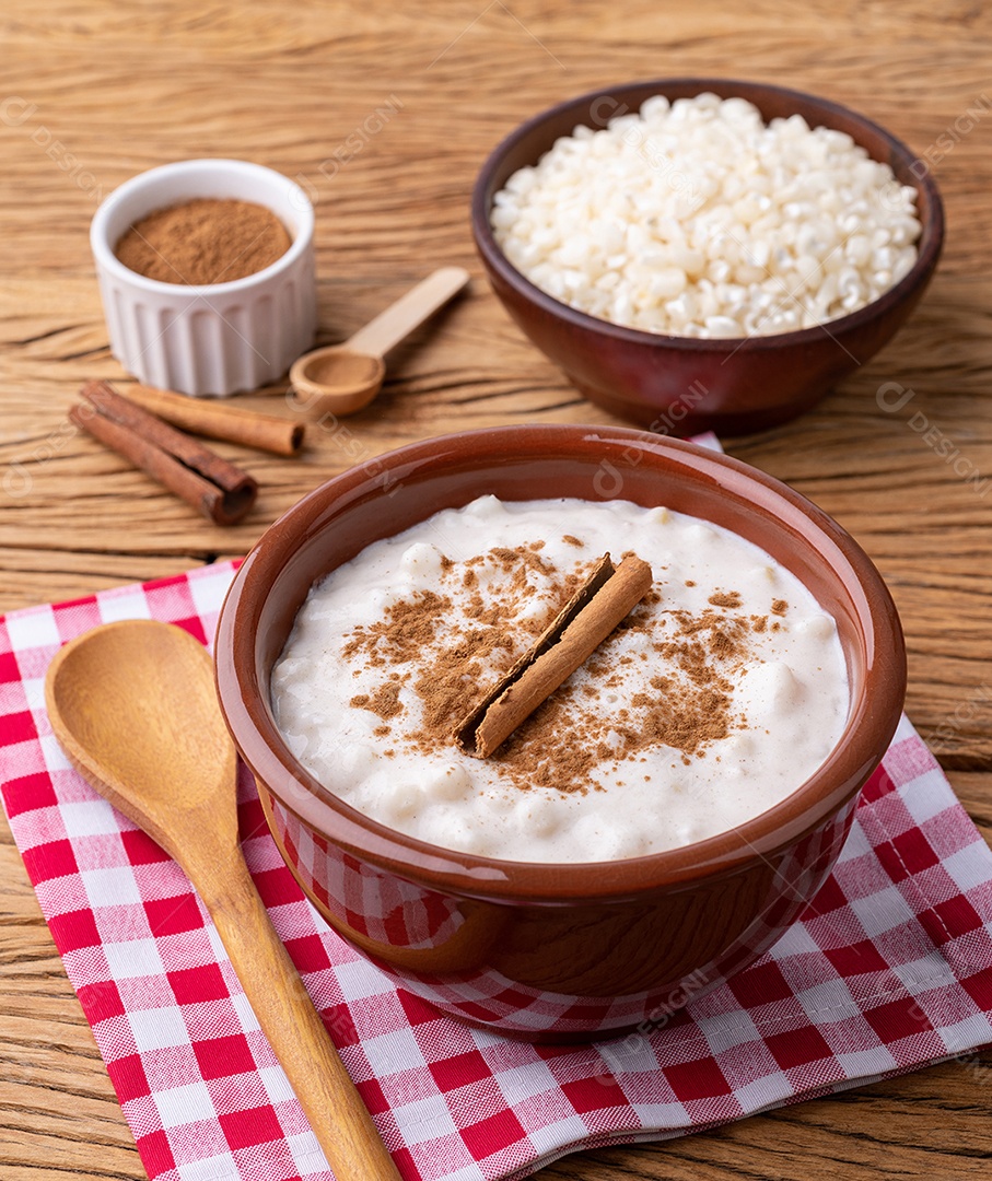 Canjica ou munguza, típico creme doce de milho branco brasileiro com canela sobre mesa de madeira.