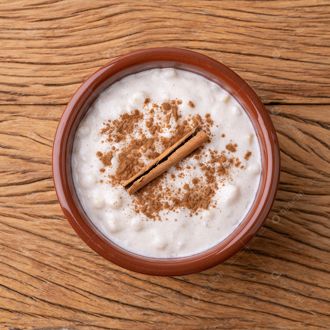 Canjica ou munguza, típico creme doce de milho branco brasileiro com canela sobre mesa de madeira.