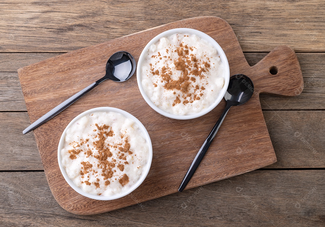 Canjica ou munguza, típico creme doce de milho branco brasileiro com canela sobre mesa de madeira.