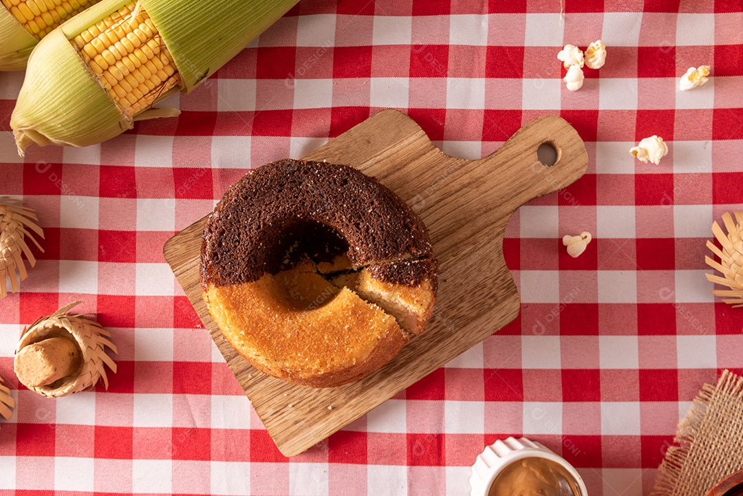 Mesa de madeira com comidas típicas da Festa Junina brasileira. espantalho