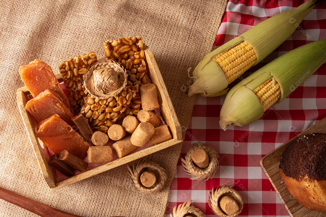 Mesa de madeira com comidas típicas da Festa Junina brasileira. espantalho