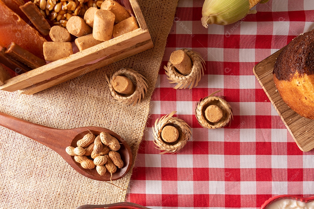 Mesa de madeira com comidas típicas da Festa Junina brasileira. espantalho