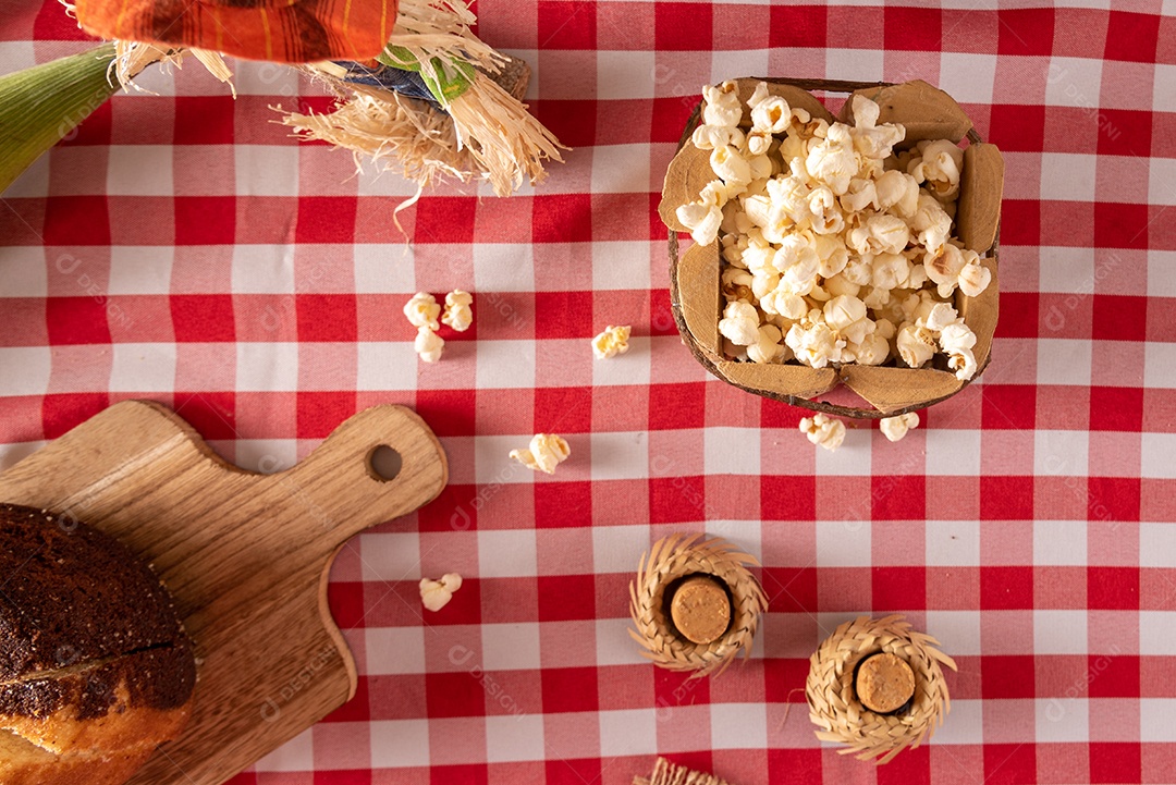 Mesa de madeira com comidas típicas da Festa Junina brasileira. espantalho
