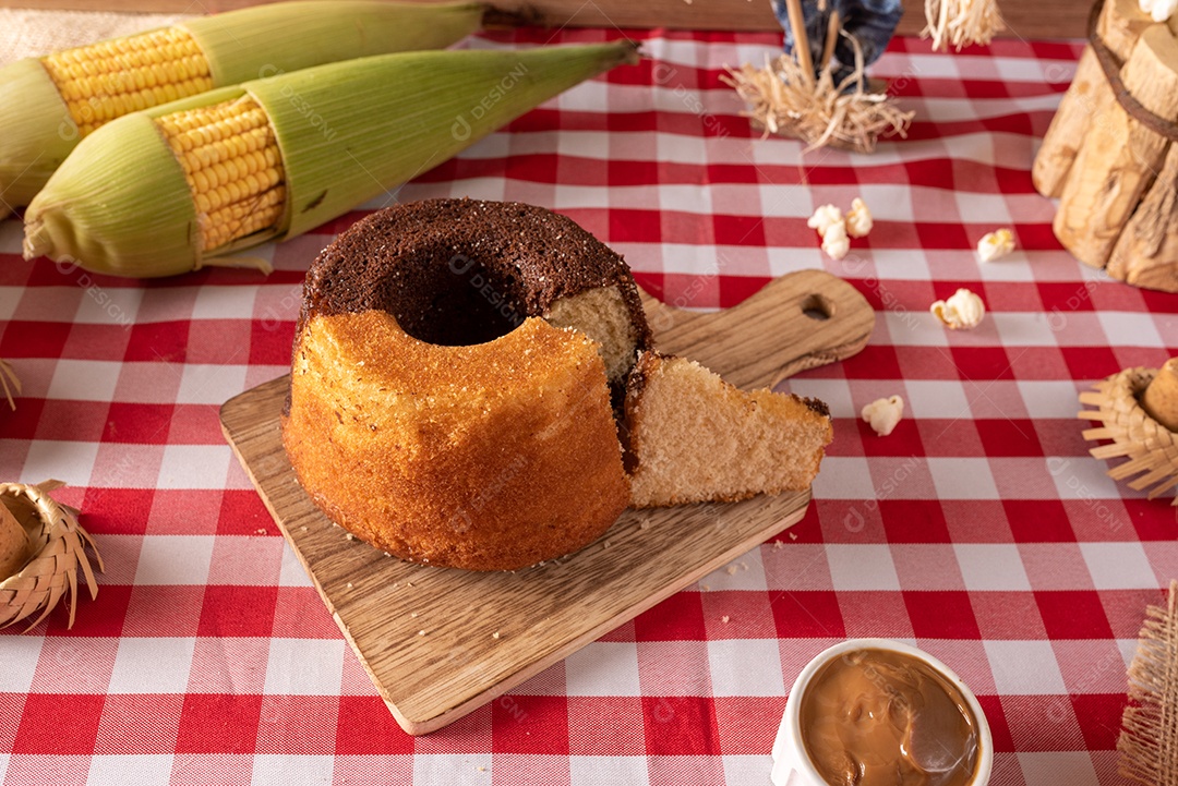 Mesa de madeira com comidas típicas da Festa Junina brasileira. espantalho