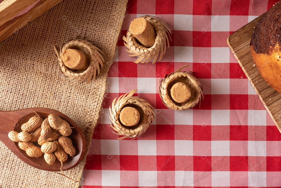 Mesa de madeira com comidas típicas da Festa Junina brasileira. espantalho
