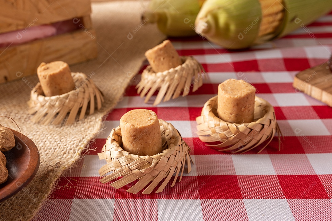 Mesa de madeira com comidas típicas da Festa Junina brasileira. espantalho