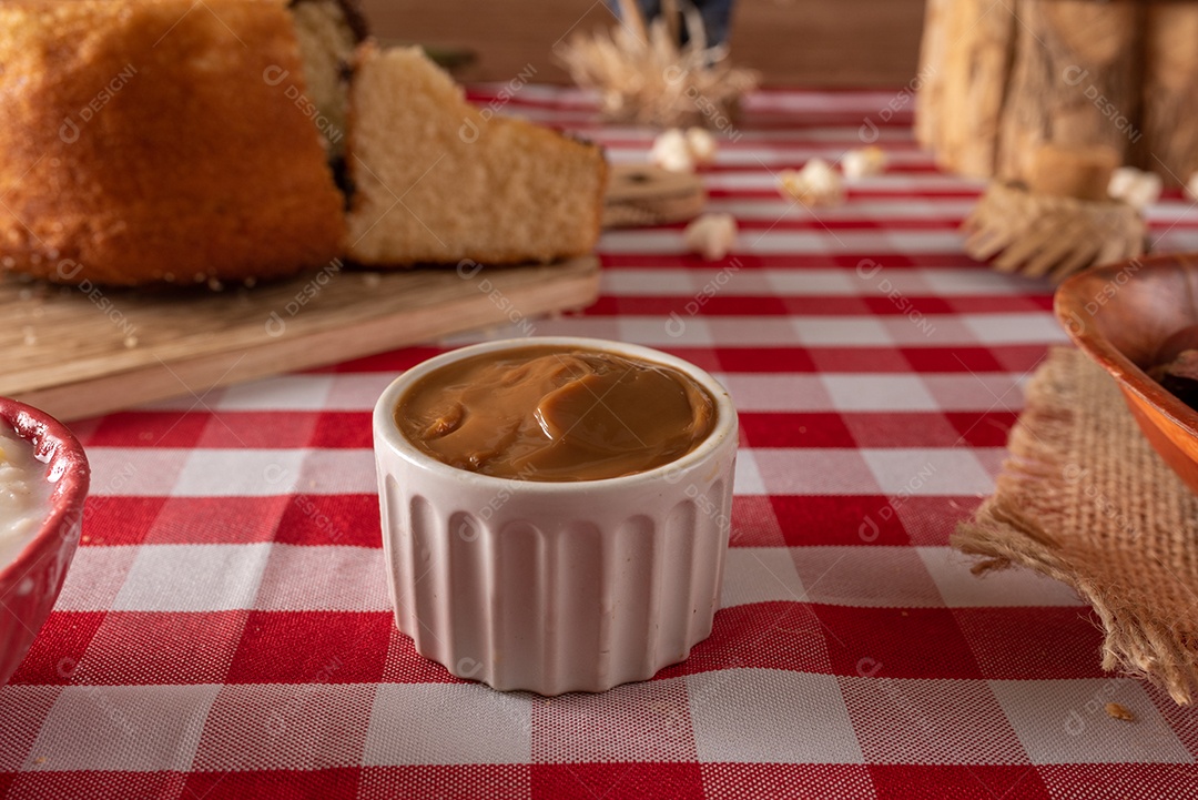Mesa de madeira com comidas típicas da Festa Junina brasileira. espantalho