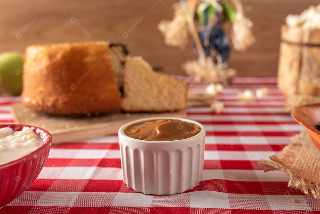 Mesa de madeira com comidas típicas da Festa Junina brasileira. espantalho
