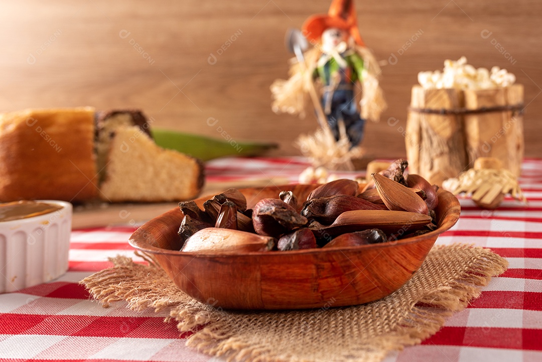 Mesa de madeira com comidas típicas da Festa Junina brasileira. espantalho