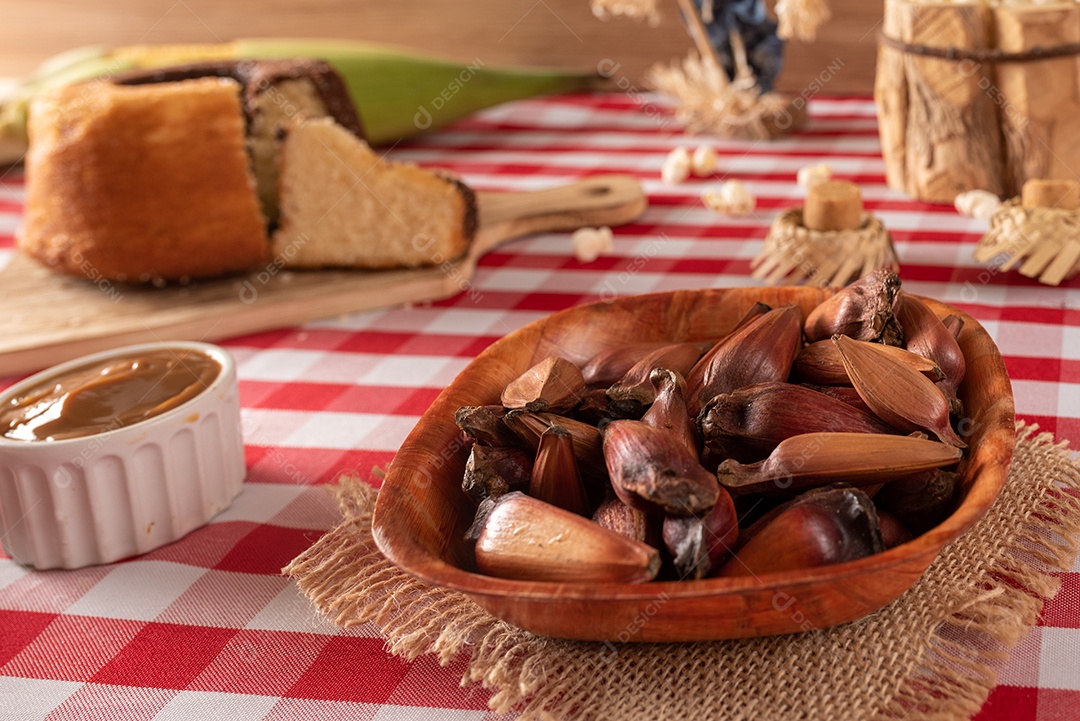 Mesa de madeira com comidas típicas da Festa Junina brasileira. espantalho