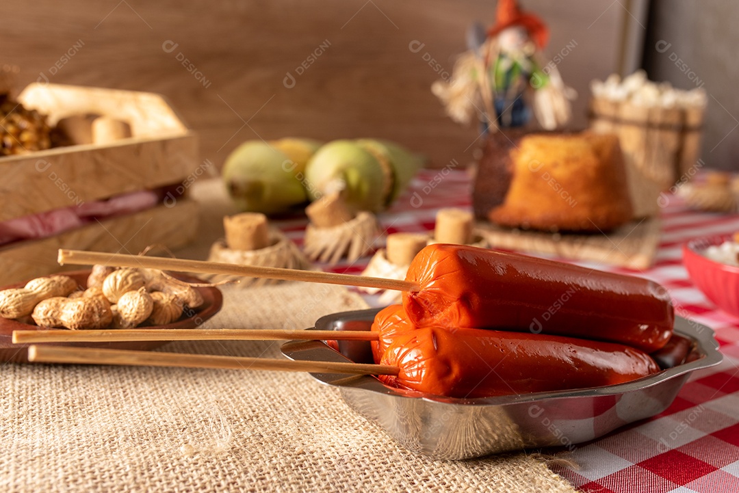 Mesa de madeira com comidas típicas da Festa Junina brasileira. espantalho