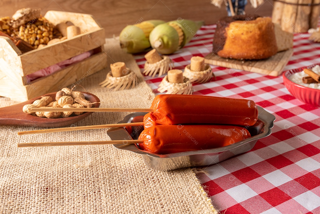 Mesa de madeira com comidas típicas da Festa Junina brasileira. espantalho