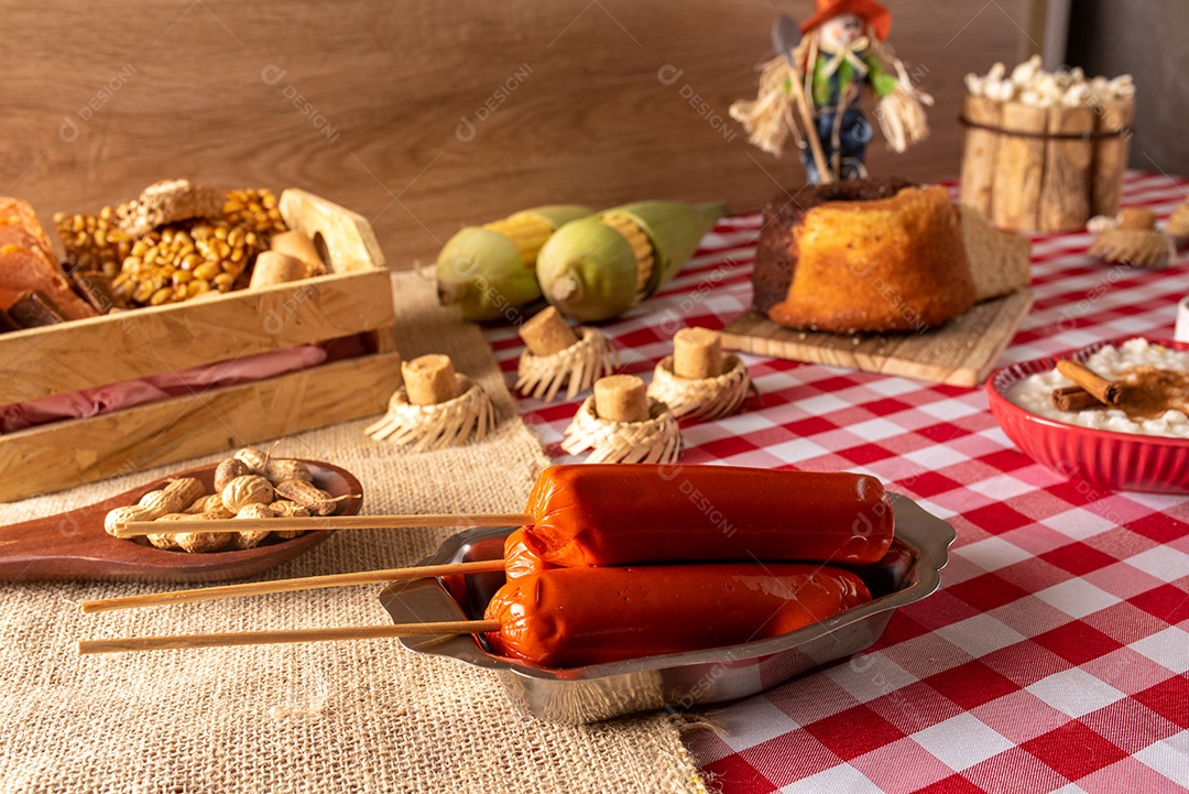 Mesa de madeira com comidas típicas da Festa Junina brasileira. espantalho