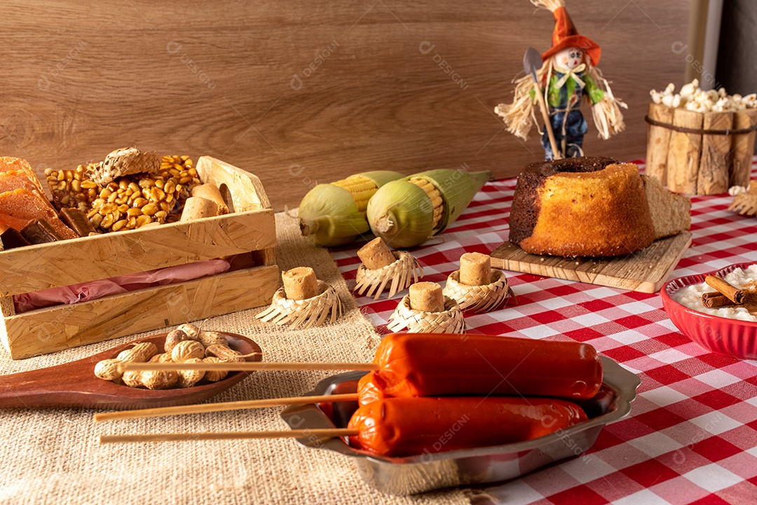 Mesa de madeira com comidas típicas da Festa Junina brasileira. espantalho