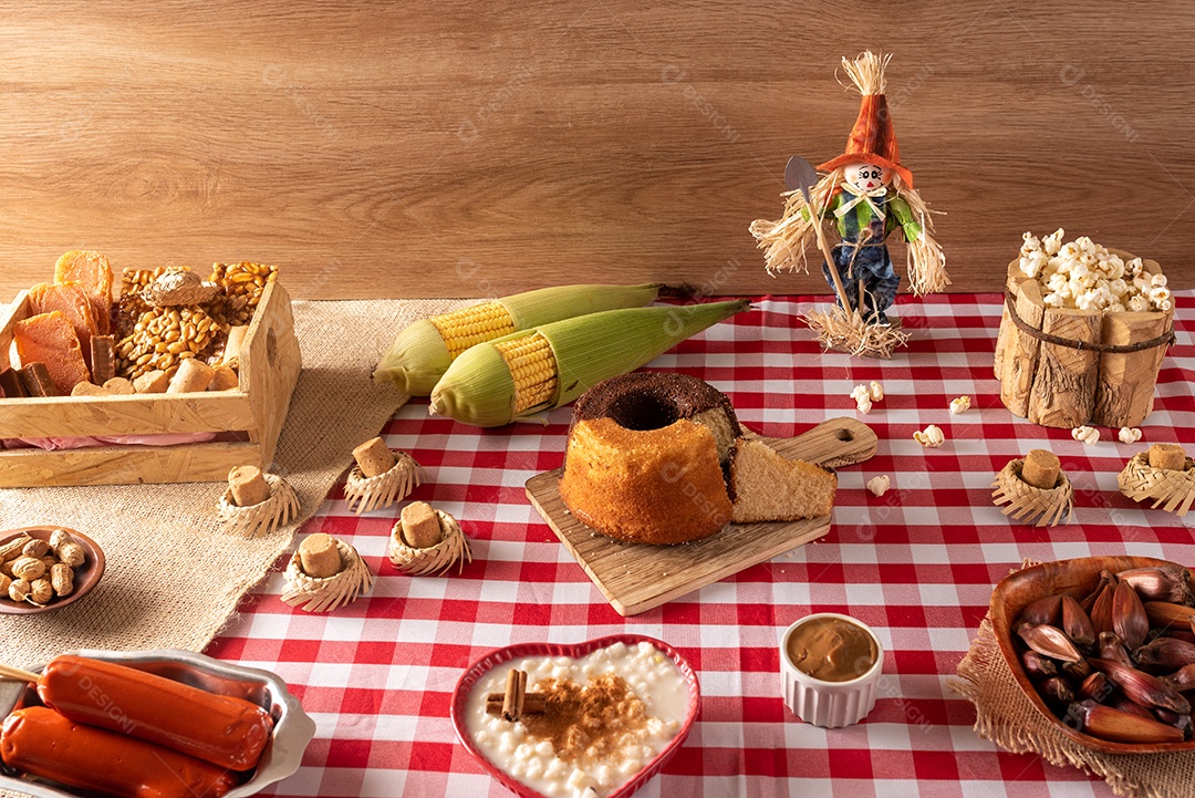 Mesa de madeira com comidas típicas da Festa Junina brasileira. espantalho