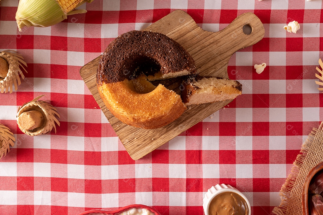 Mesa de madeira com comidas típicas da Festa Junina brasileira. espantalho