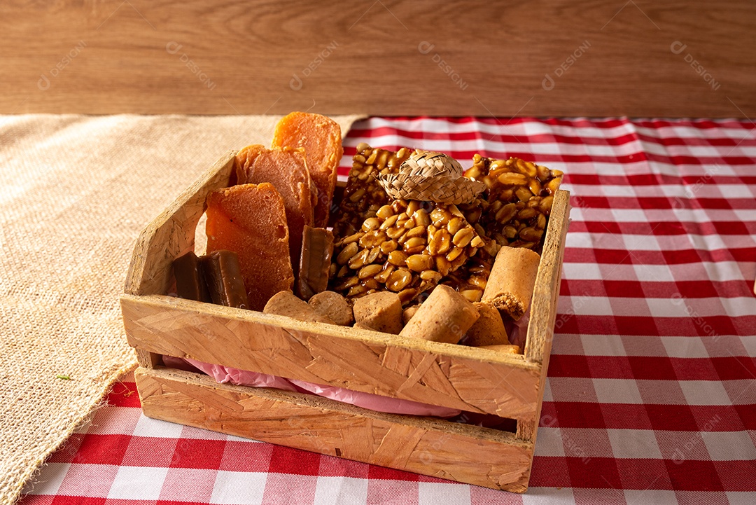Mesa de madeira com comidas típicas da Festa Junina brasileira. espantalho