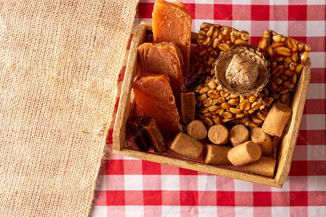 Mesa de madeira com comidas típicas da Festa Junina brasileira. espantalho