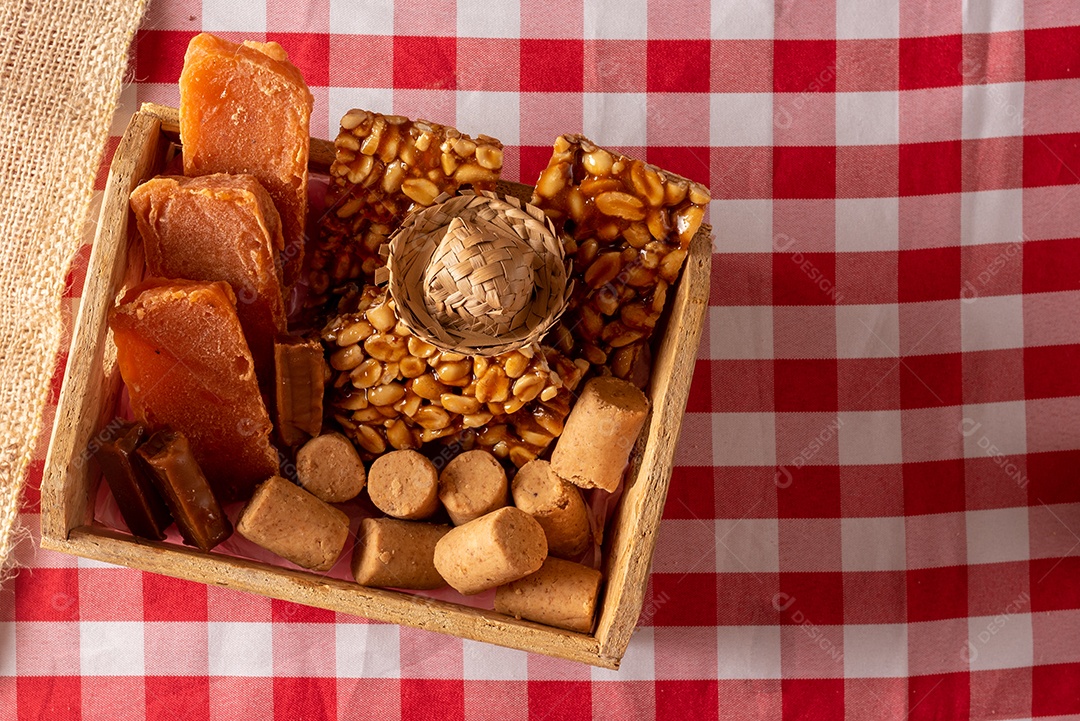 Mesa de madeira com comidas típicas da Festa Junina brasileira. espantalho