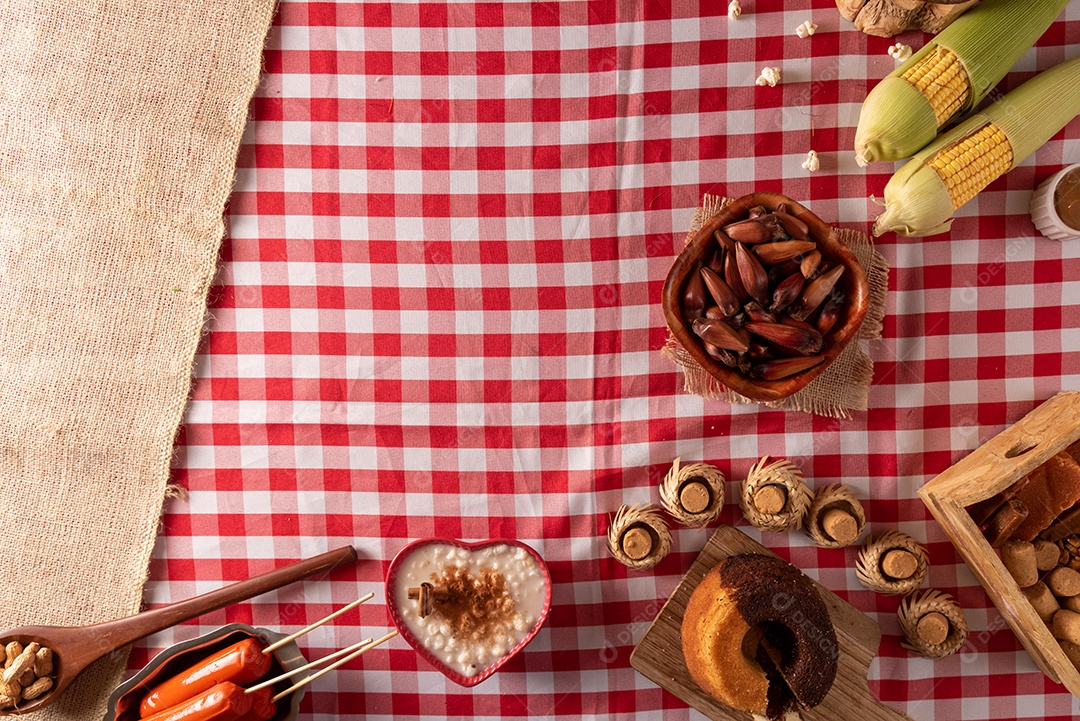 Mesa de madeira com comidas típicas da Festa Junina brasileira. espantalho