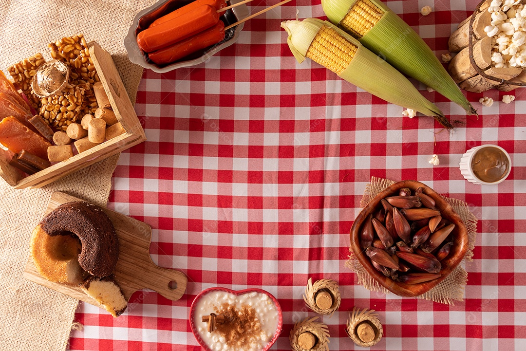 Mesa de madeira com comidas típicas da Festa Junina brasileira. espantalho
