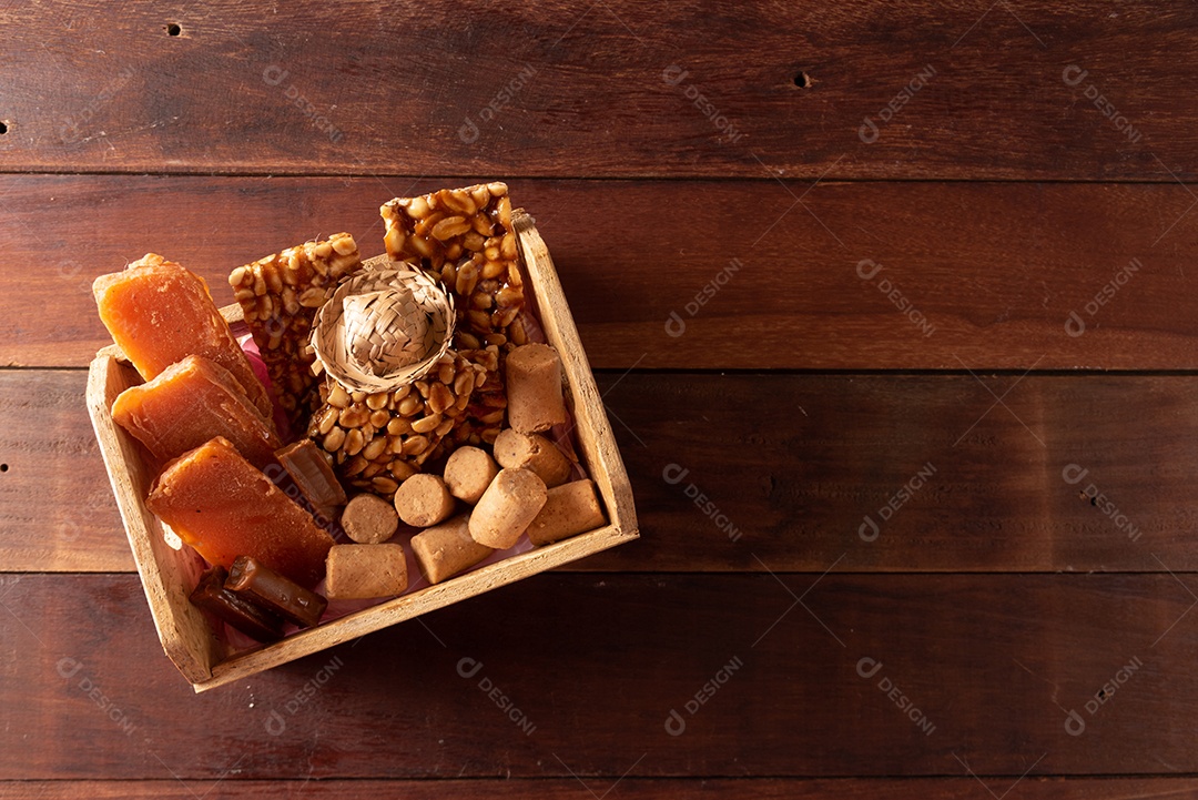 Mesa de madeira com comidas típicas da Festa Junina brasileira. espantalho