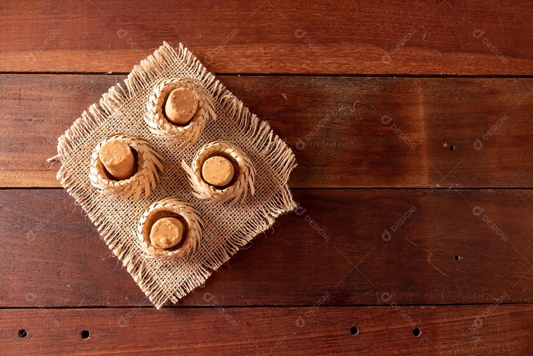 Mesa de madeira com comidas típicas da Festa Junina brasileira. espantalho