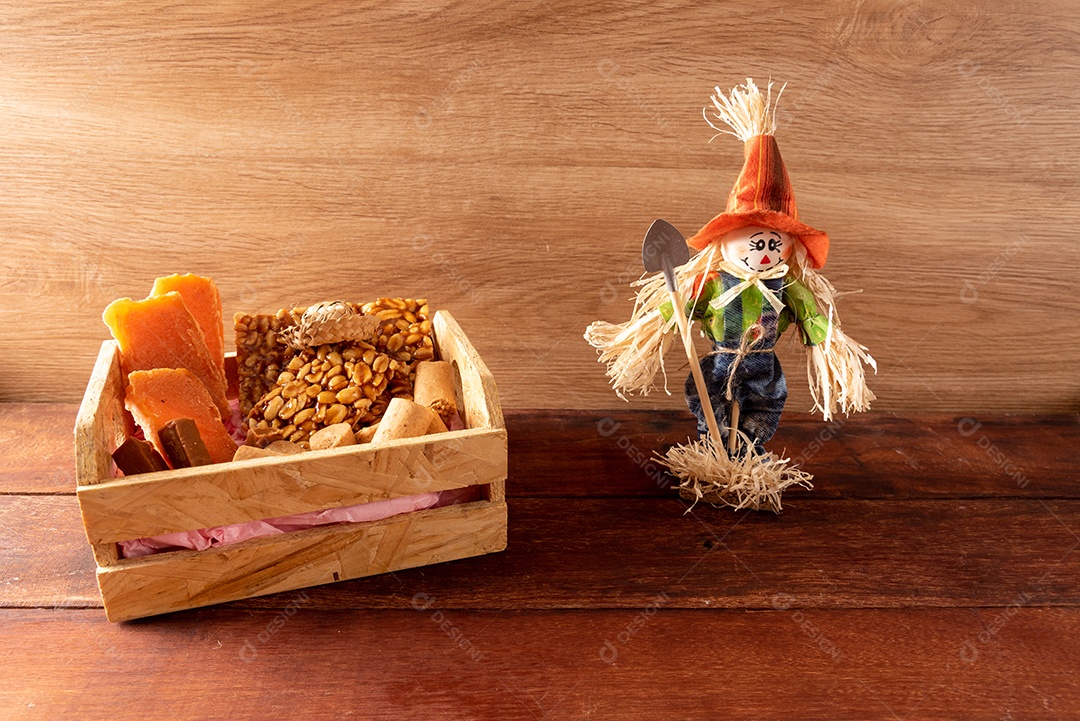 Mesa de madeira com comidas típicas da Festa Junina brasileira. espantalho