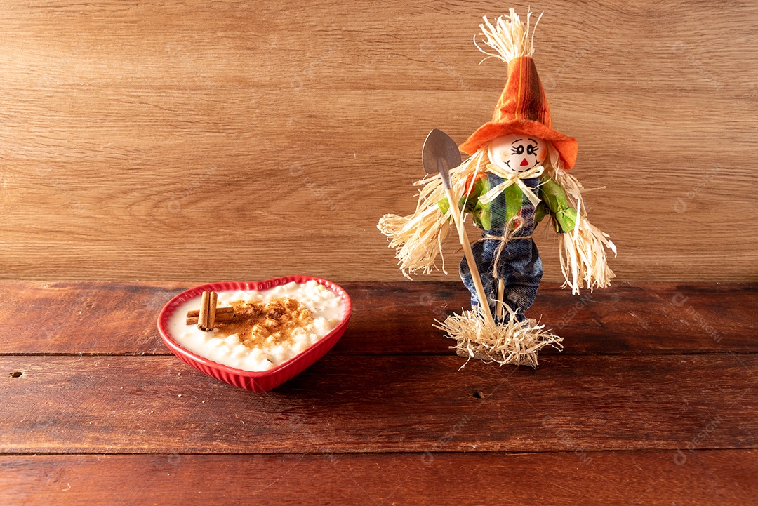 Mesa de madeira com comidas típicas da Festa Junina brasileira. espantalho
