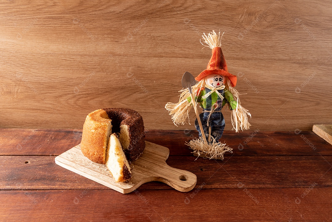 Mesa de madeira com comidas típicas da Festa Junina brasileira. espantalho