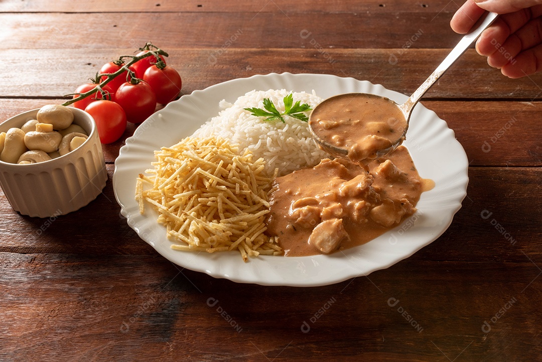 Strogonoff de frango acompanhado de arroz, salada e batata palha.
