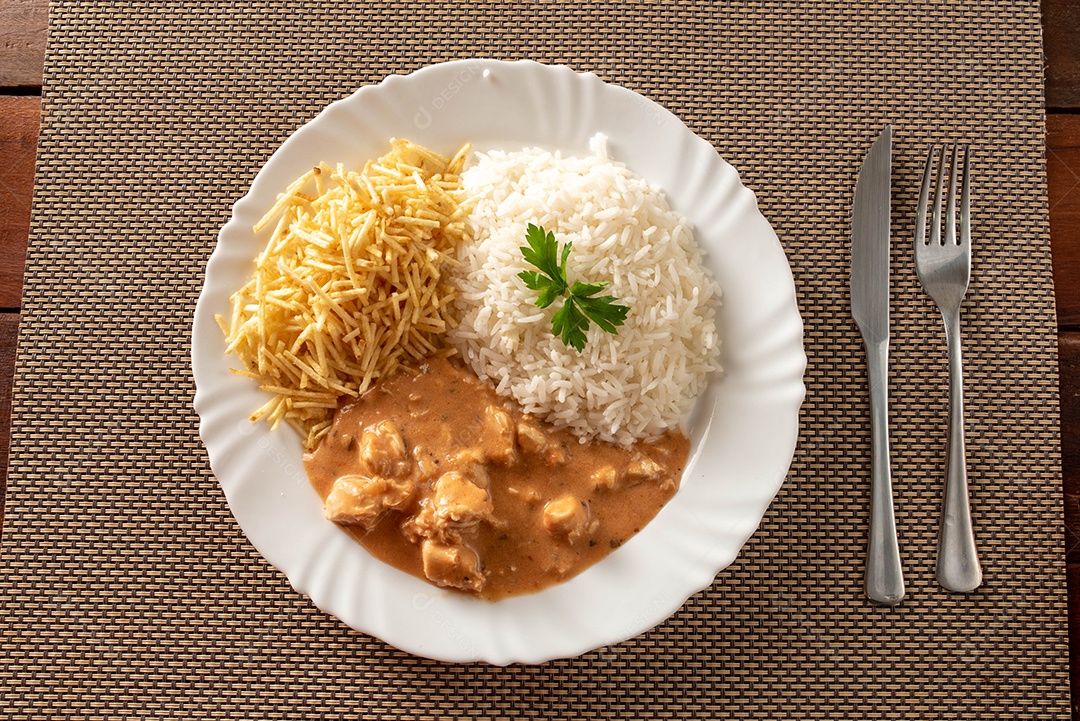 Strogonoff de frango acompanhado de arroz, salada e batata palha.
