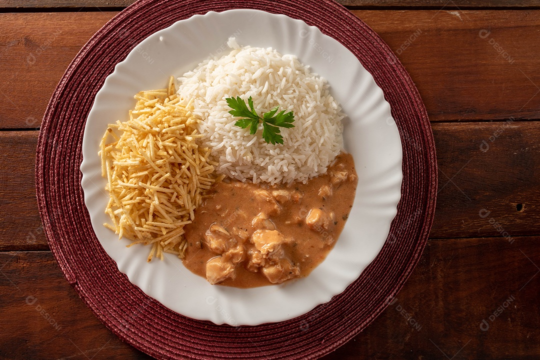 Strogonoff de frango acompanhado de arroz, salada e batata palha.