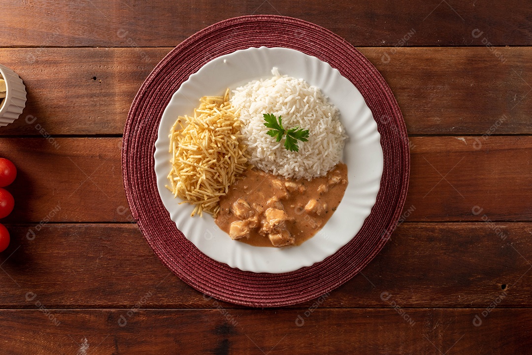 Strogonoff de frango acompanhado de arroz, salada e batata palha.