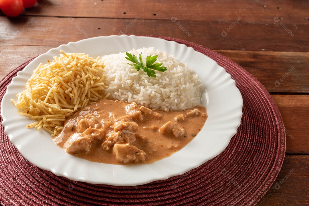 Strogonoff de frango acompanhado de arroz, salada e batata palha.