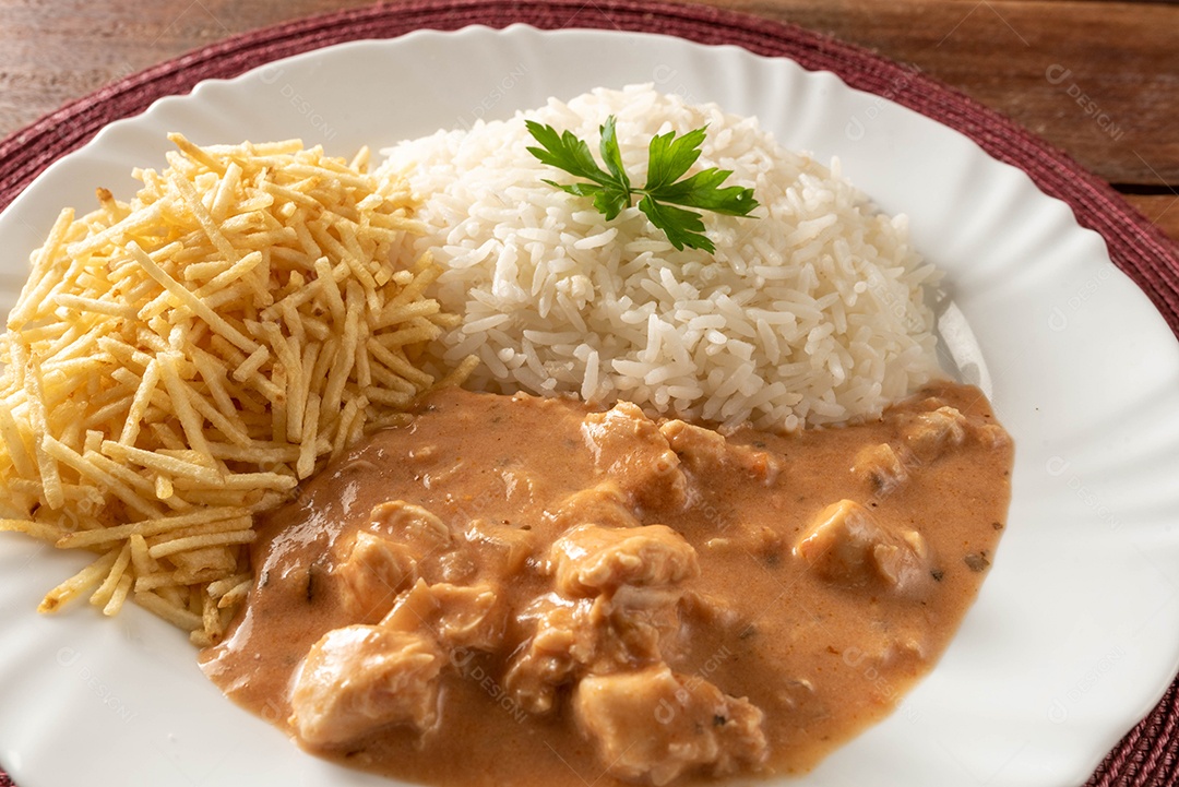 Strogonoff de frango acompanhado de arroz, salada e batata palha.
