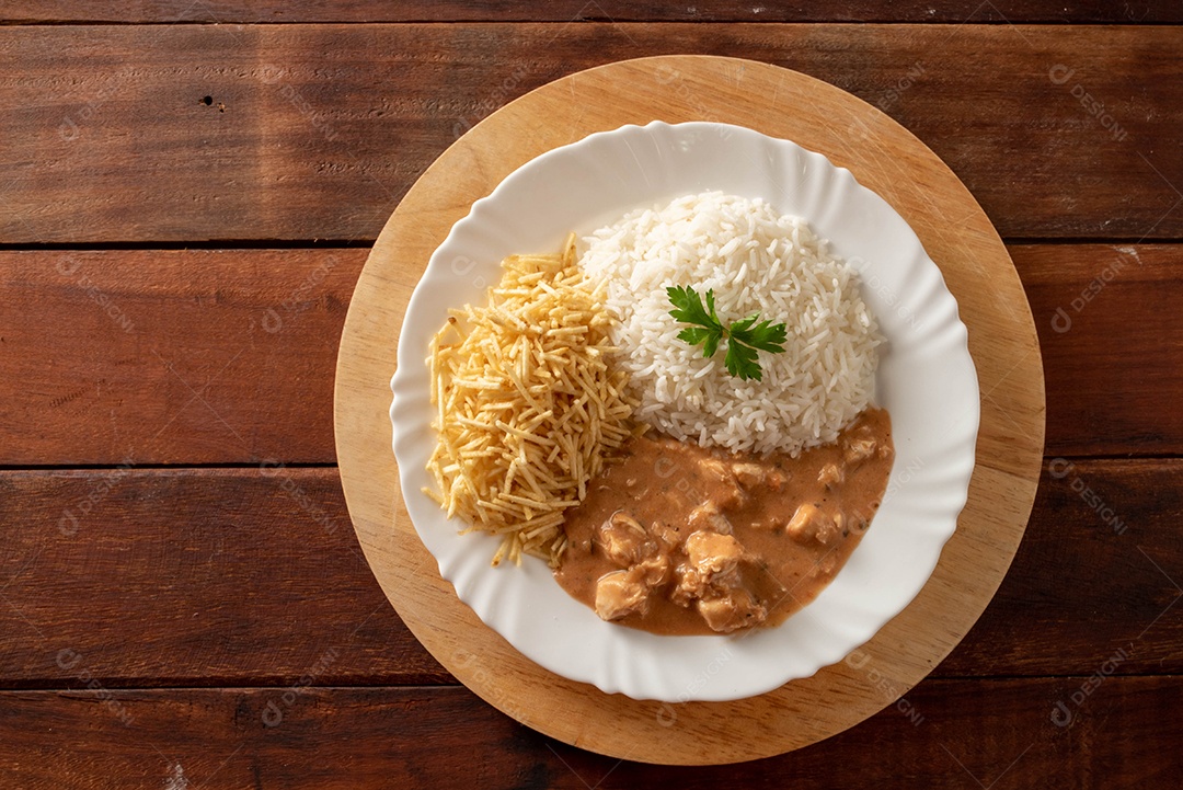 Strogonoff de frango acompanhado de arroz, salada e batata palha.