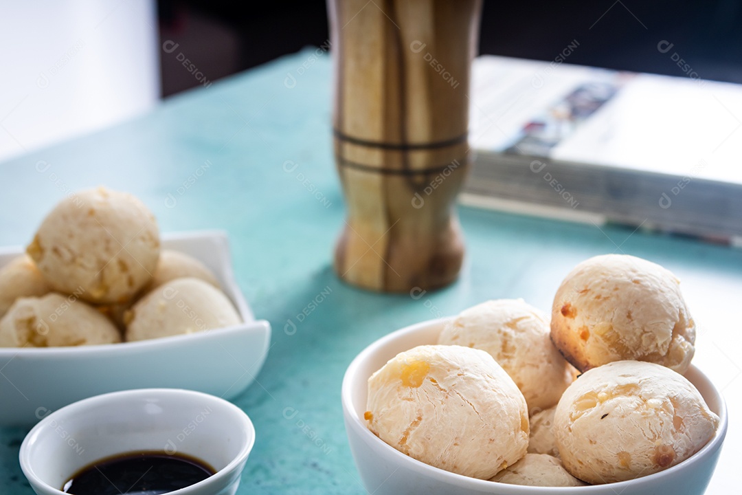 Delicioso pão de queijo, prato típico brasileiro, sobre uma mesa com fundo verde e parede branca.