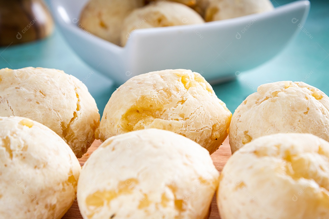 Delicioso pão de queijo, prato típico brasileiro, sobre uma mesa com fundo verde e parede branca.
