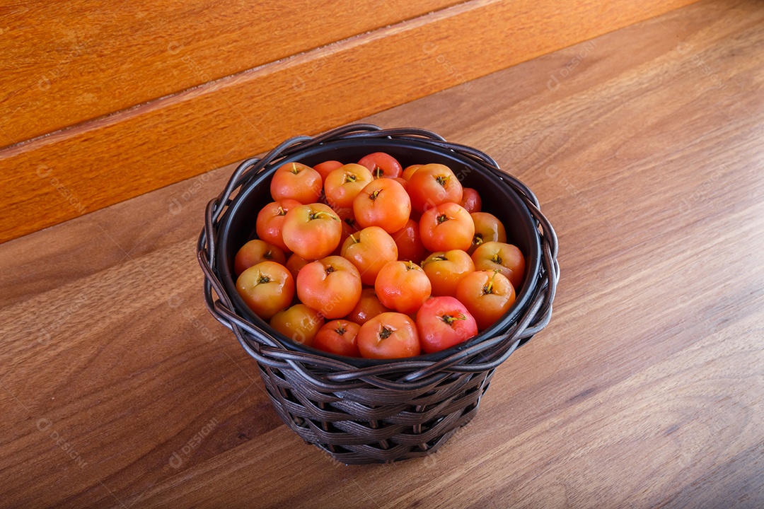 Pote preto com acerolas na mesa