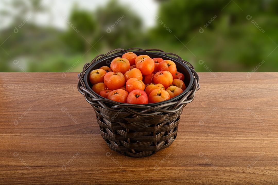 Pote preto com acerolas na mesa